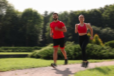 Image of Man and woman in sportswear running outdoors on sunny morning, motion blue effect