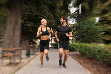 Image of Man and woman in sportswear running outdoors, motion blue effect