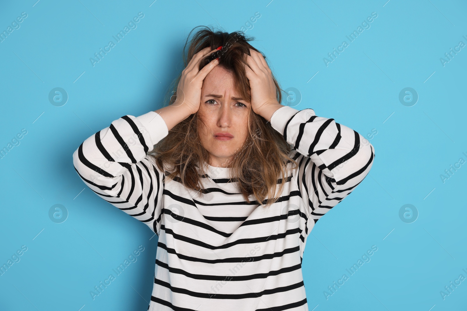 Woman suffering from hangover on light blue background Photo of Woman suffering from hangover on light blue background
