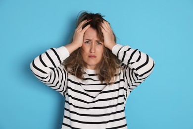 Photo of Woman suffering from hangover on light blue background