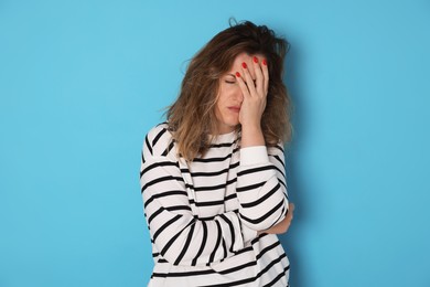 Photo of Woman suffering from hangover on light blue background