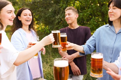 Photo of Group of happy friends clinking glasses of beer outdoors