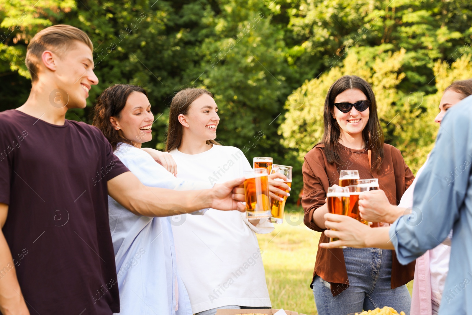 Photo of Group of happy friends clinking glasses of beer outdoors