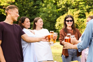 Photo of Group of happy friends clinking glasses of beer outdoors