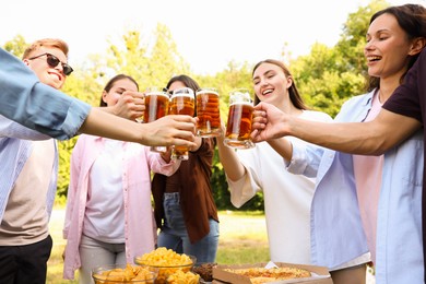 Photo of Group of happy friends clinking glasses of beer outdoors