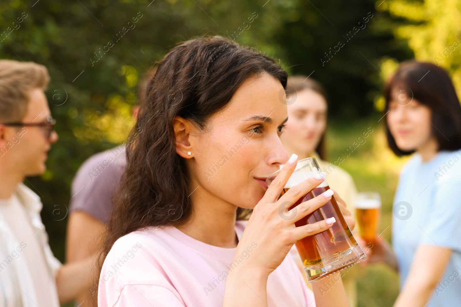Photo of Group of happy friends having fun and drinking beer outdoors, selective focus