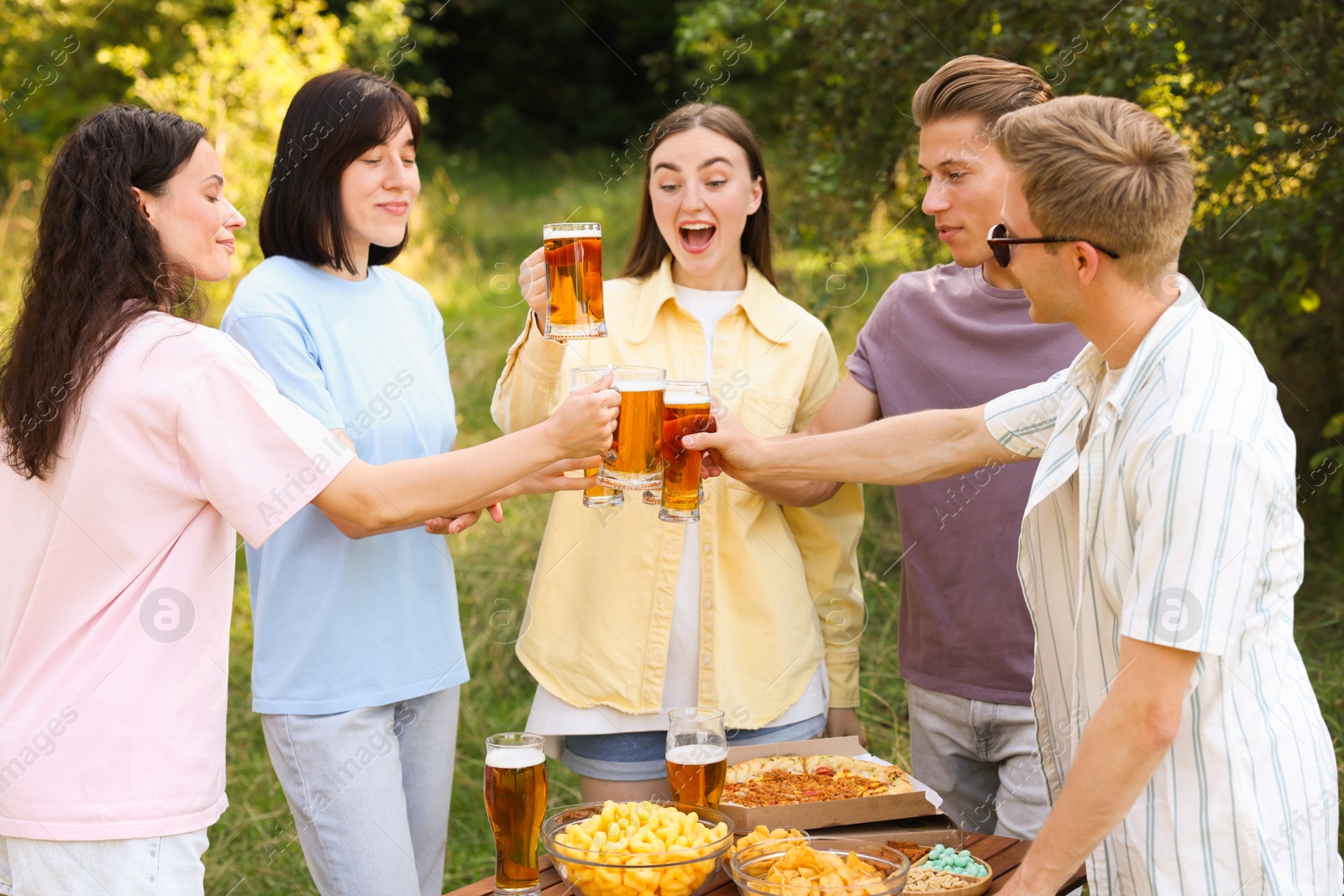 Photo of Group of happy friends clinking glasses of beer outdoors