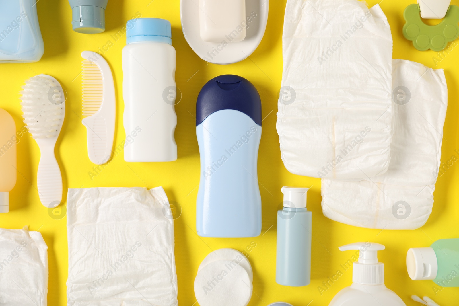 Photo of Baby accessories and cosmetic products on yellow background, flat lay