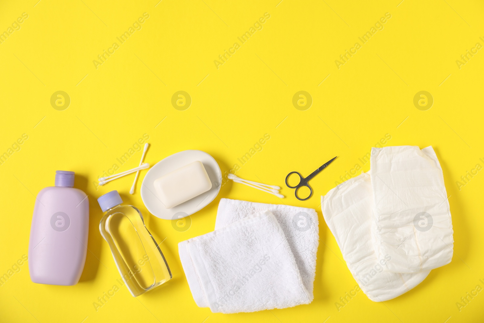 Photo of Baby accessories and cosmetic products on yellow background, flat lay. Space for text