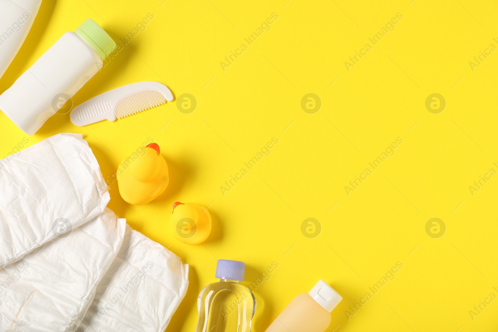 Photo of Baby accessories and cosmetic products on yellow background, flat lay. Space for text