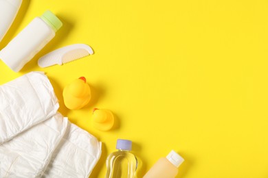 Photo of Baby accessories and cosmetic products on yellow background, flat lay. Space for text