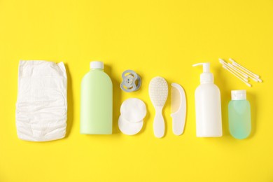 Photo of Baby accessories and cosmetic products on yellow background, flat lay