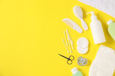 Photo of Baby accessories and cosmetic products on yellow background, flat lay. Space for text