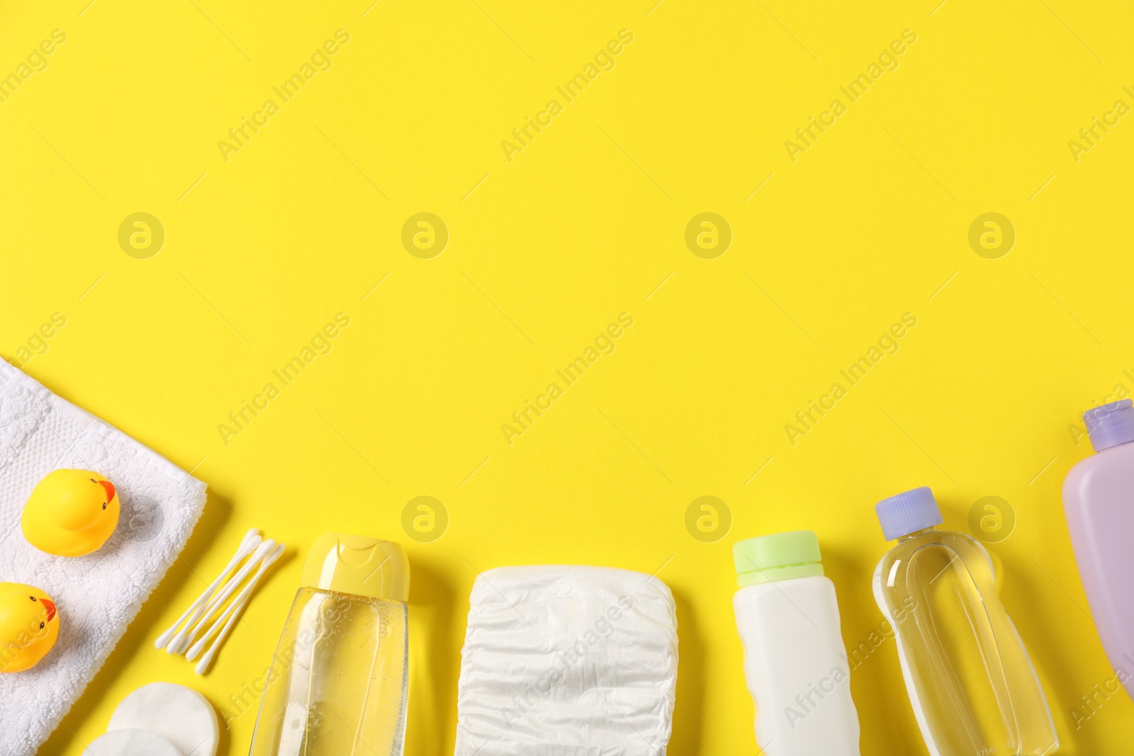 Baby accessories and cosmetic products on yellow background, flat lay. Space for text Photo of Baby accessories and cosmetic products on yellow background, flat lay. Space for text