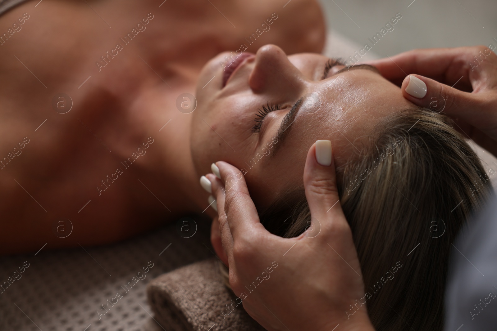 Beautiful woman receiving facial massage on couch in spa salon, closeup Photo of Beautiful woman receiving facial massage on couch in spa salon, closeup