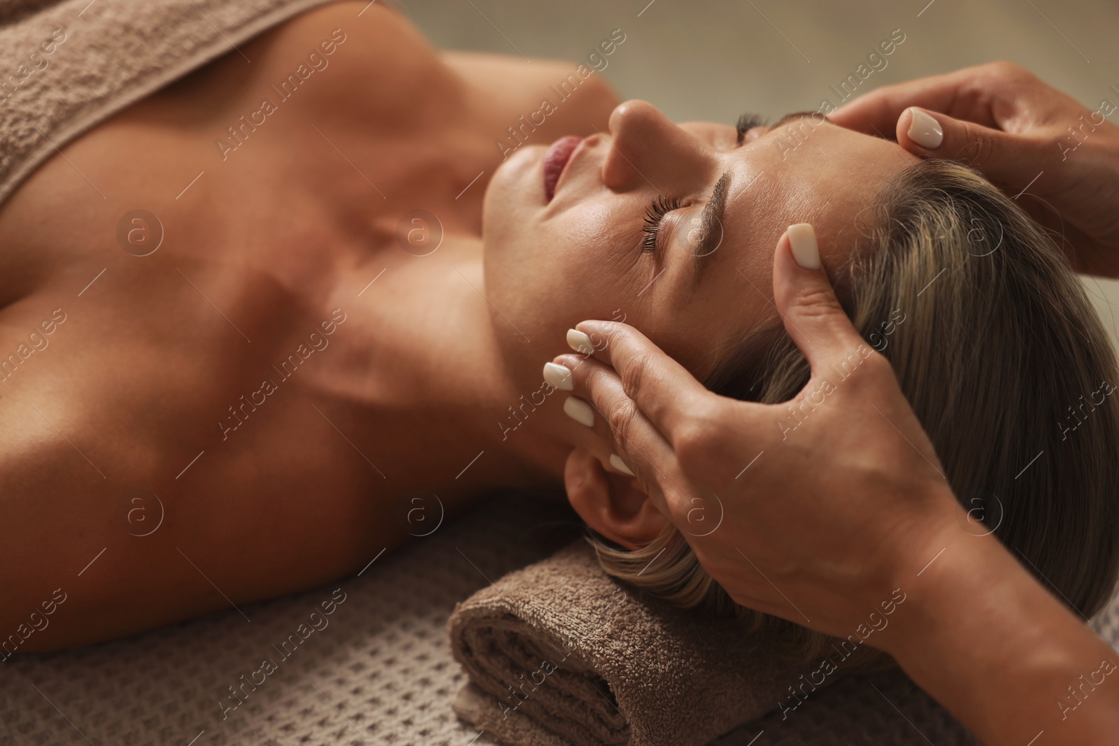Beautiful woman receiving facial massage on couch in spa salon, closeup Photo of Beautiful woman receiving facial massage on couch in spa salon, closeup