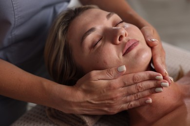 Photo of Beautiful woman receiving facial massage in spa salon, closeup