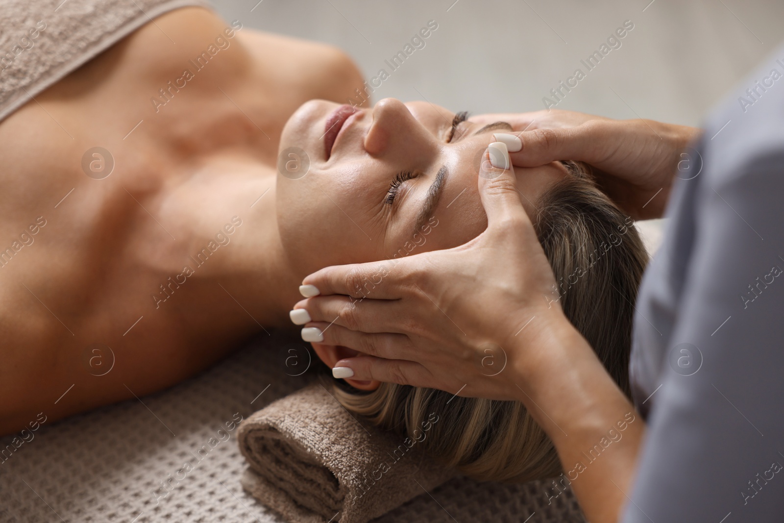 Beautiful woman receiving facial massage on couch in spa salon, closeup Photo of Beautiful woman receiving facial massage on couch in spa salon, closeup