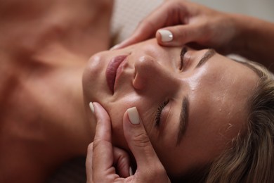 Photo of Beautiful woman receiving facial massage, closeup view