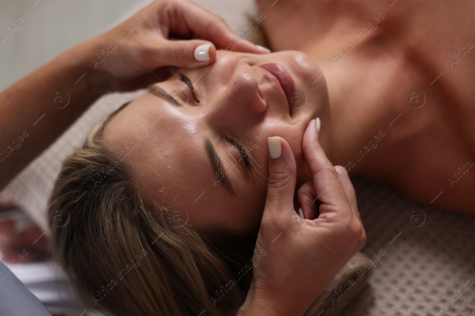 Beautiful woman receiving facial massage on couch indoors, closeup Photo of Beautiful woman receiving facial massage on couch indoors, closeup