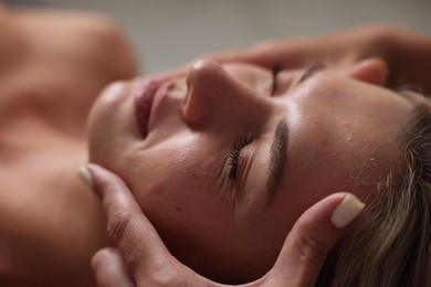 Photo of Beautiful woman receiving facial massage, closeup view