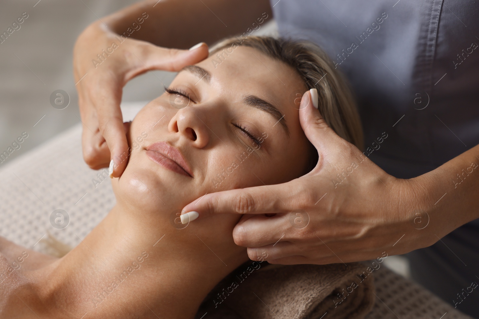 Beautiful woman receiving facial massage on couch in spa salon, closeup Photo of Beautiful woman receiving facial massage on couch in spa salon, closeup