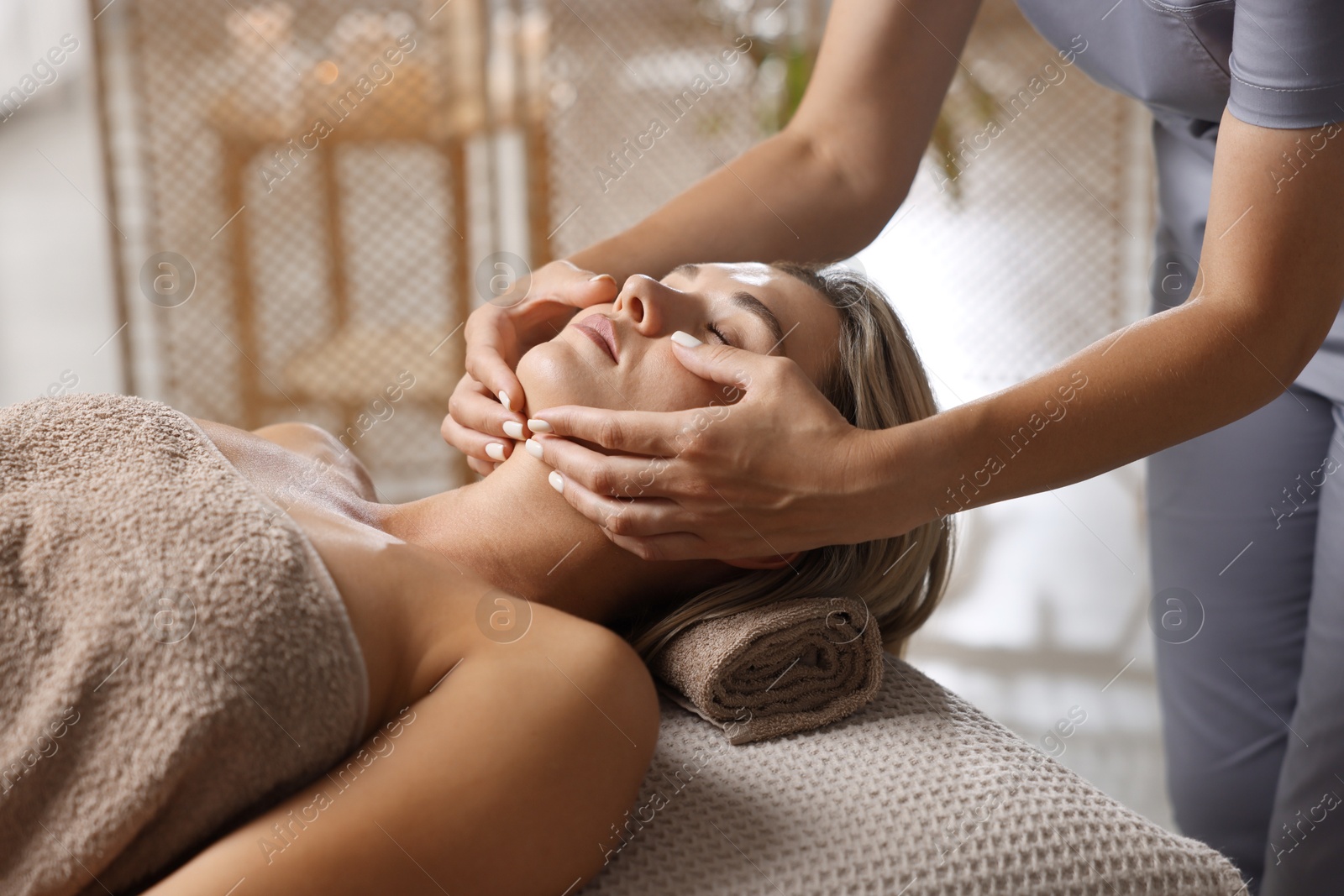 Beautiful woman receiving facial massage on couch in spa salon, closeup Photo of Beautiful woman receiving facial massage on couch in spa salon, closeup