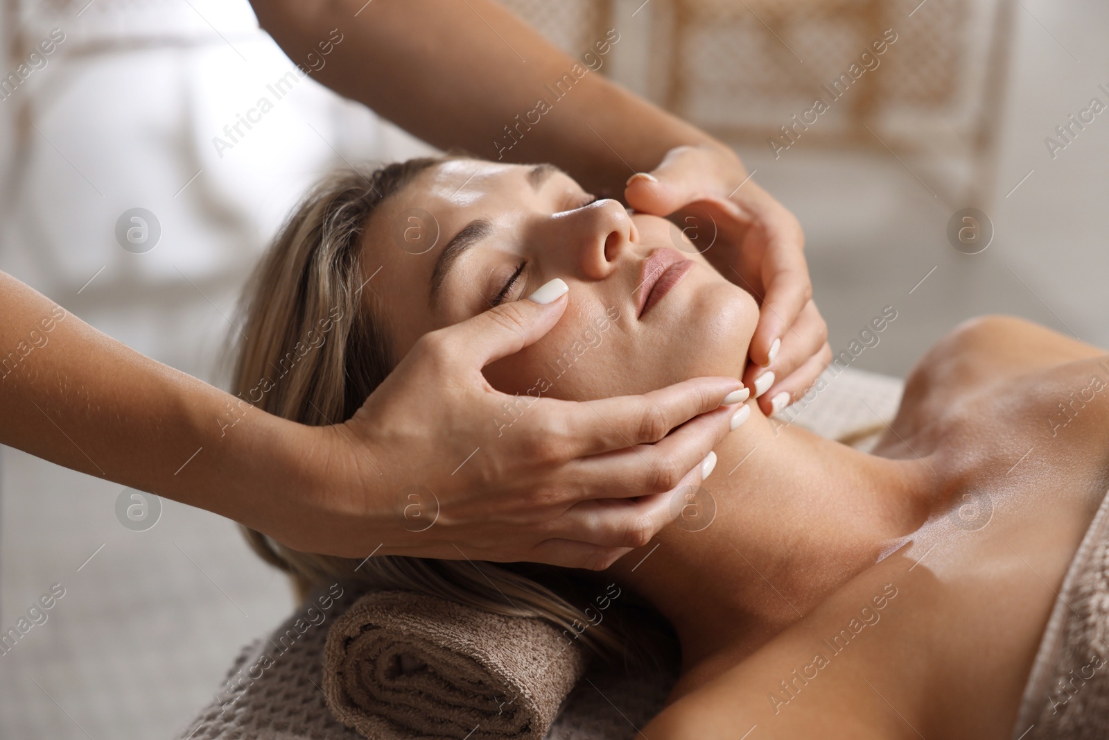 Beautiful woman receiving facial massage on couch in spa salon, closeup Photo of Beautiful woman receiving facial massage on couch in spa salon, closeup