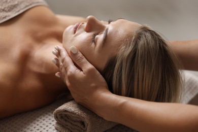 Photo of Beautiful woman receiving facial massage on blurred beige background, closeup