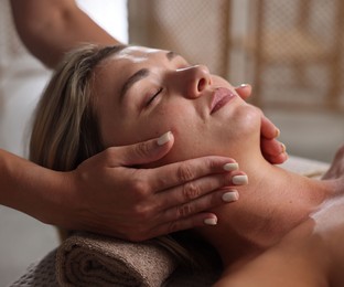 Photo of Beautiful woman receiving facial massage in spa salon, closeup