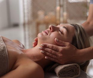 Photo of Beautiful woman receiving facial massage in spa salon, closeup