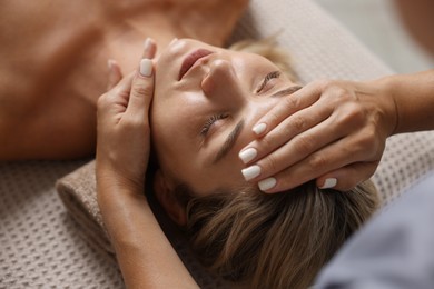 Photo of Beautiful woman receiving facial massage on couch, closeup