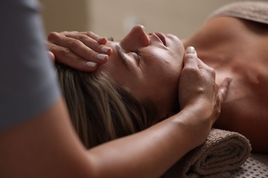 Photo of Beautiful woman receiving facial massage on blurred beige background, closeup