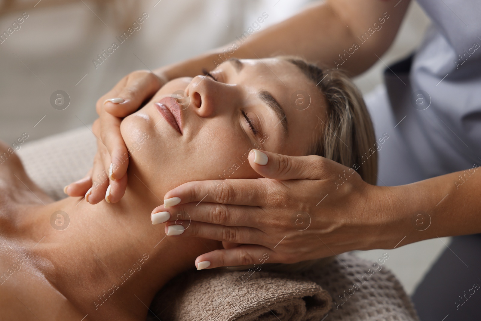 Beautiful woman receiving facial massage on couch indoors, closeup Photo of Beautiful woman receiving facial massage on couch indoors, closeup