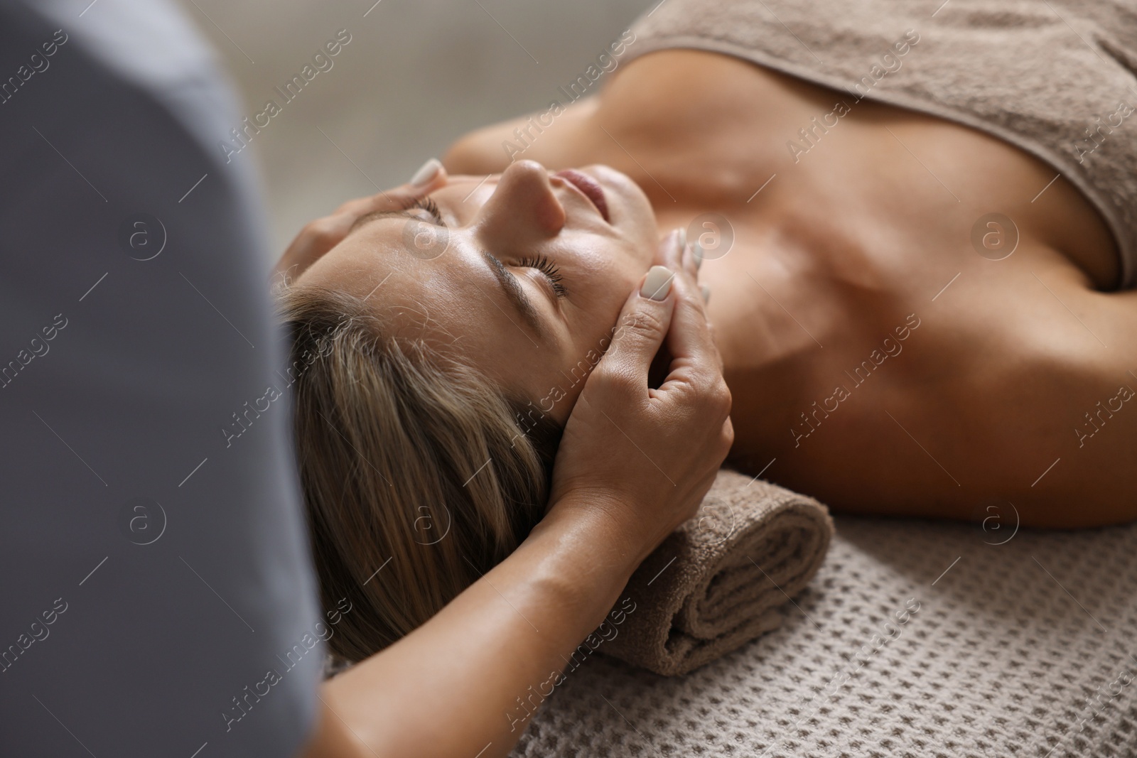 Beautiful woman receiving facial massage on couch indoors, closeup Photo of Beautiful woman receiving facial massage on couch indoors, closeup