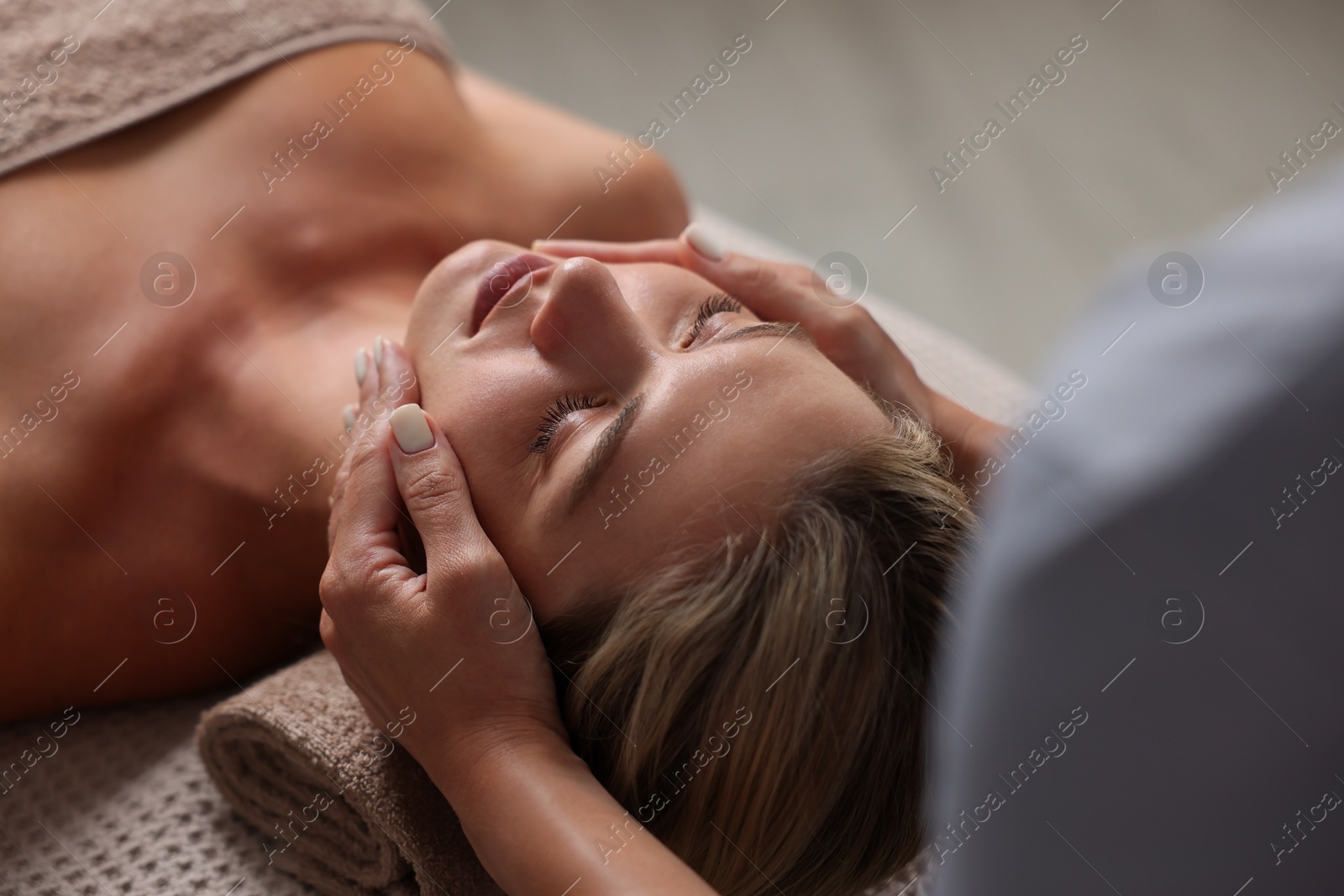 Beautiful woman receiving facial massage on couch indoors, closeup Photo of Beautiful woman receiving facial massage on couch indoors, closeup