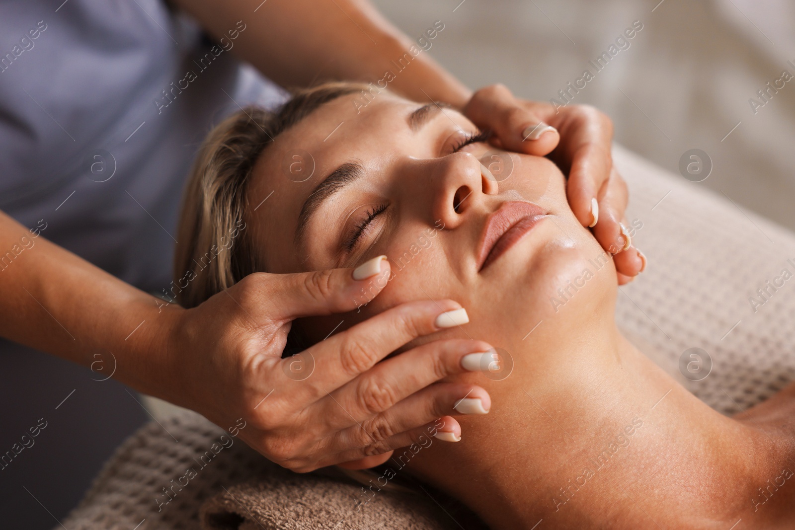Beautiful woman receiving facial massage on couch indoors, closeup Photo of Beautiful woman receiving facial massage on couch indoors, closeup