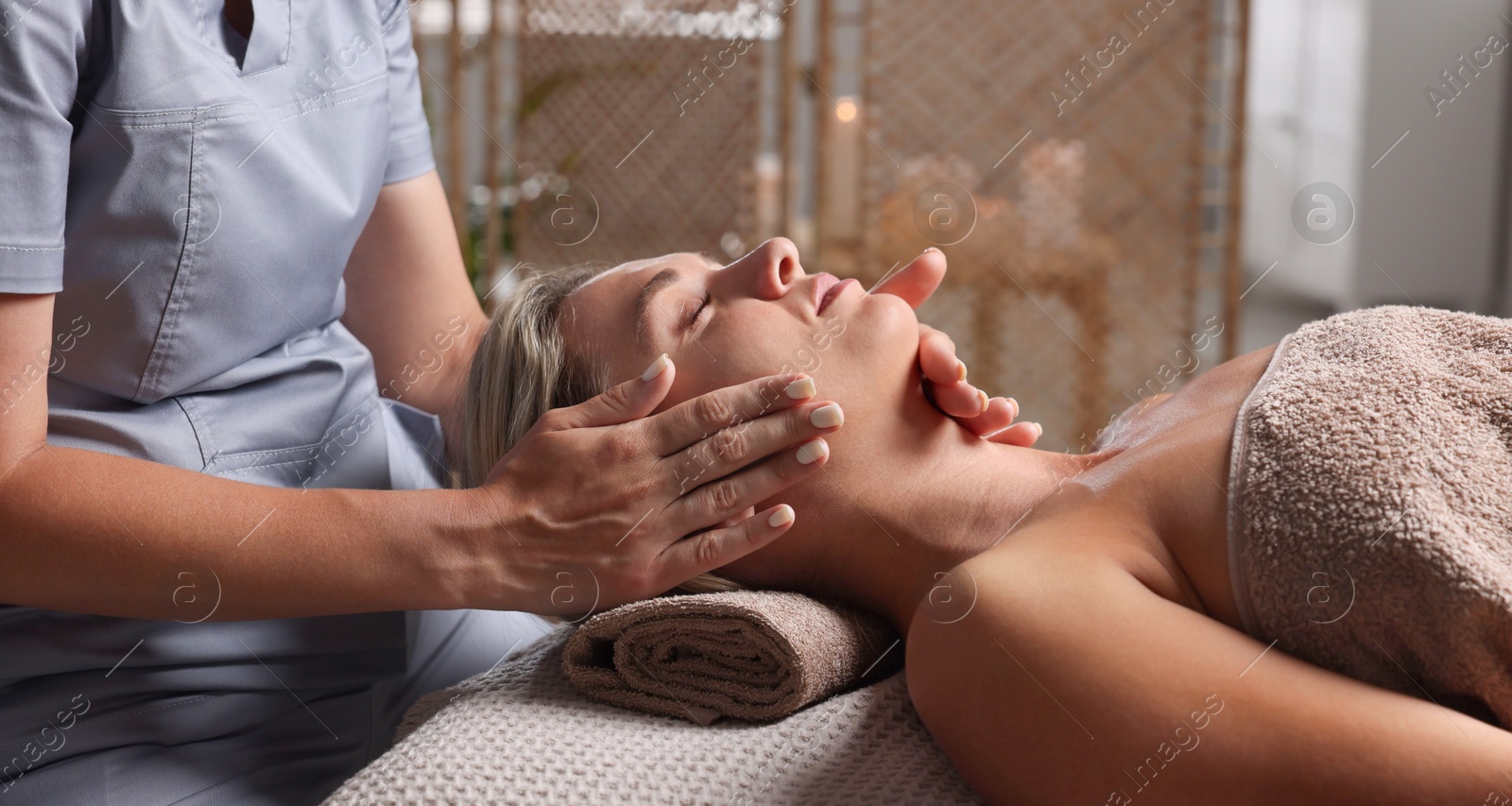 Beautiful woman receiving facial massage on couch in spa salon, closeup Photo of Beautiful woman receiving facial massage on couch in spa salon, closeup