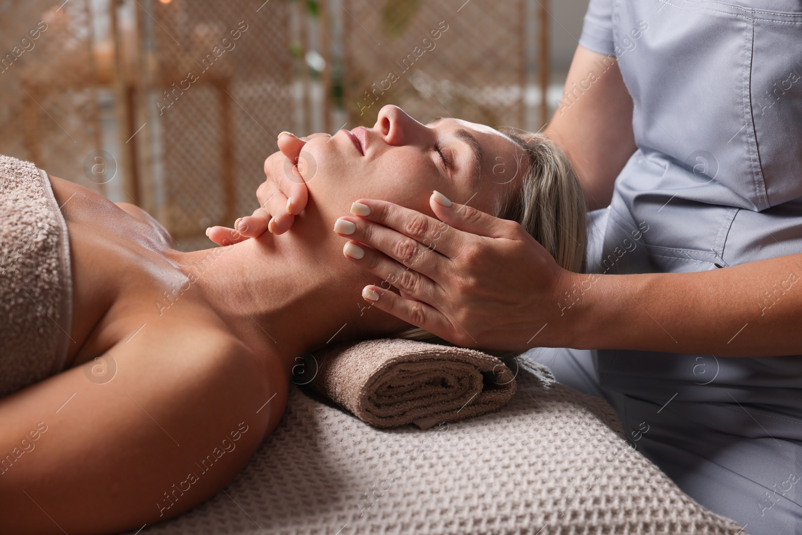 Beautiful woman receiving facial massage on couch in spa salon, closeup Photo of Beautiful woman receiving facial massage on couch in spa salon, closeup
