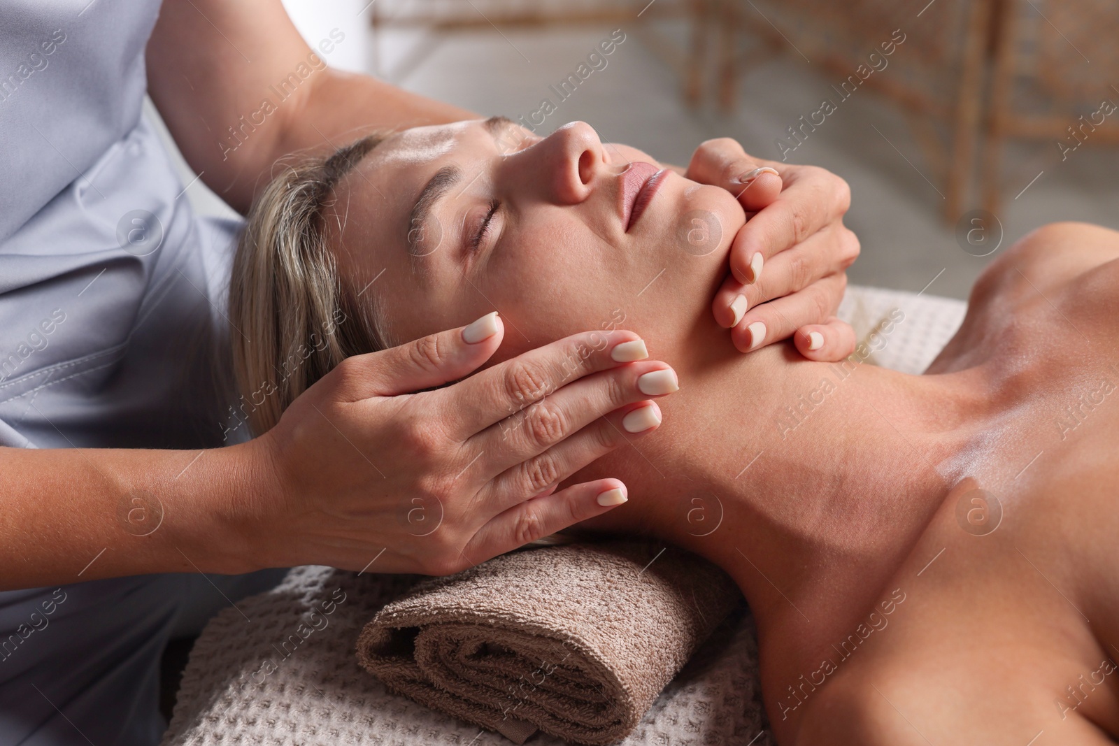 Beautiful woman receiving facial massage on couch in spa salon, closeup Photo of Beautiful woman receiving facial massage on couch in spa salon, closeup