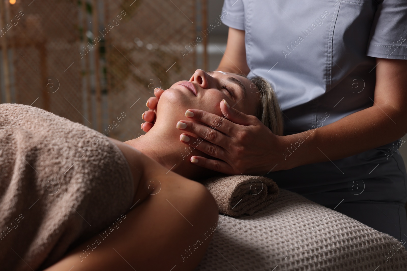Beautiful woman receiving facial massage on couch in spa salon, closeup Photo of Beautiful woman receiving facial massage on couch in spa salon, closeup