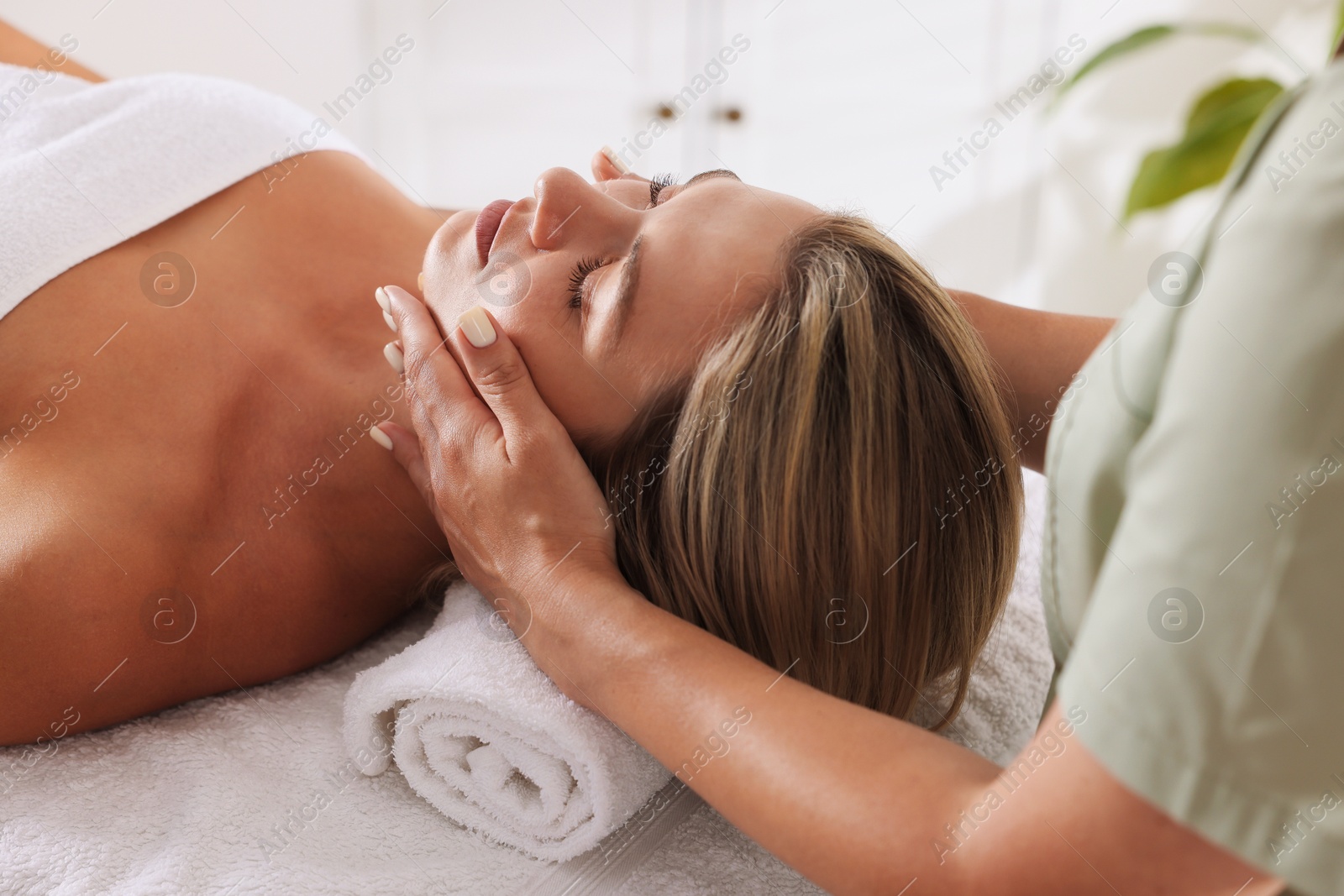 Beautiful woman receiving facial massage on couch in spa salon, closeup Photo of Beautiful woman receiving facial massage on couch in spa salon, closeup