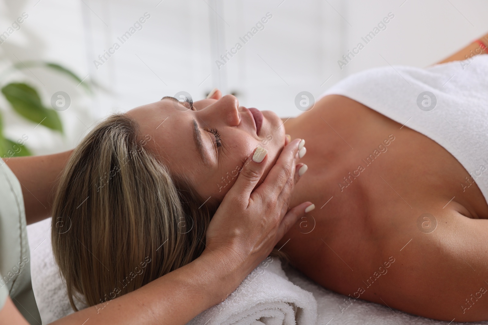 Beautiful woman receiving facial massage on couch in spa salon, closeup Photo of Beautiful woman receiving facial massage on couch in spa salon, closeup