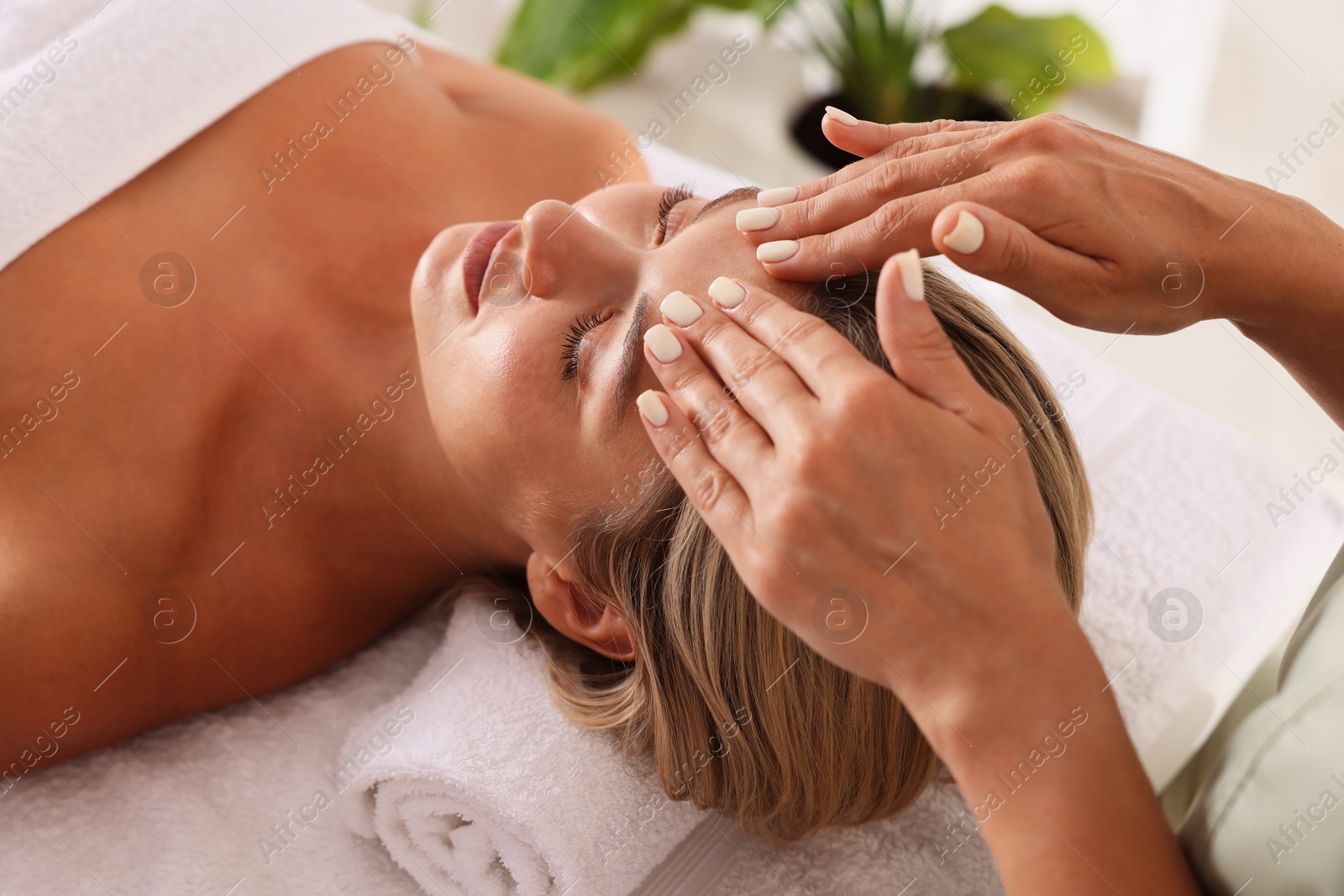 Beautiful woman receiving facial massage on couch in spa salon, closeup Photo of Beautiful woman receiving facial massage on couch in spa salon, closeup