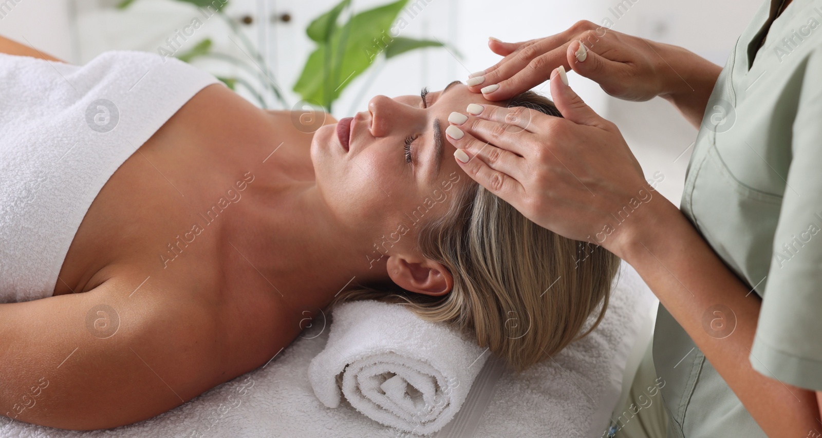 Beautiful woman receiving facial massage on couch in spa salon, closeup Photo of Beautiful woman receiving facial massage on couch in spa salon, closeup