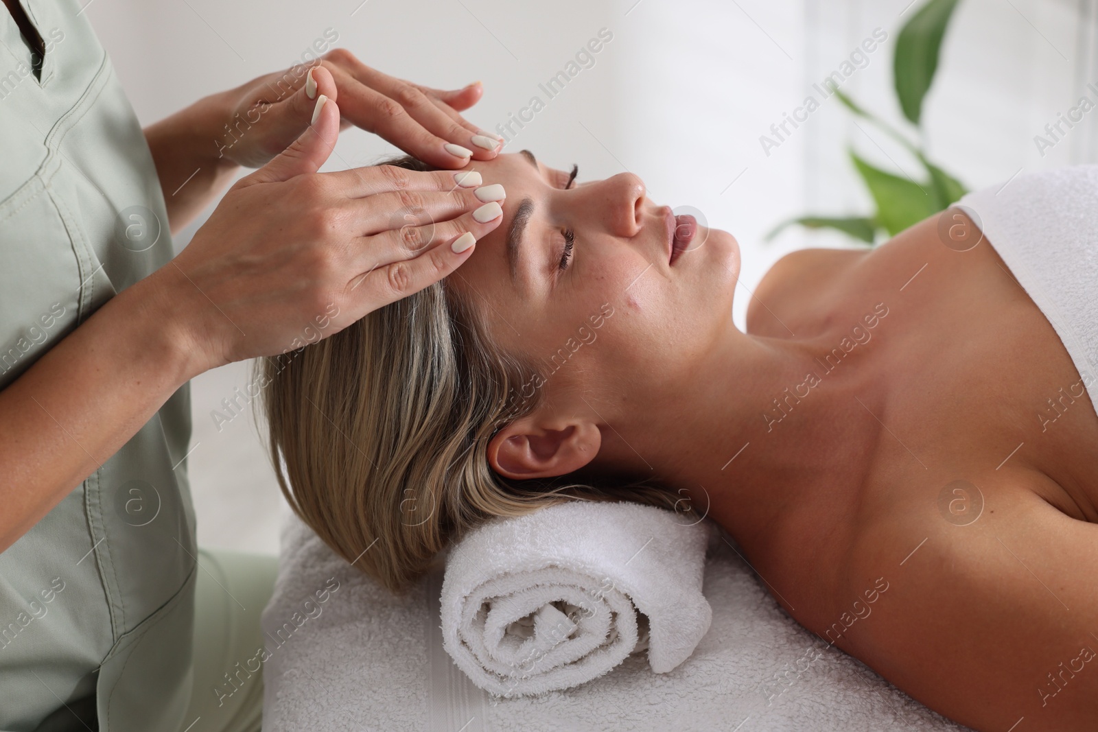 Beautiful woman receiving facial massage on couch in spa salon, closeup Photo of Beautiful woman receiving facial massage on couch in spa salon, closeup