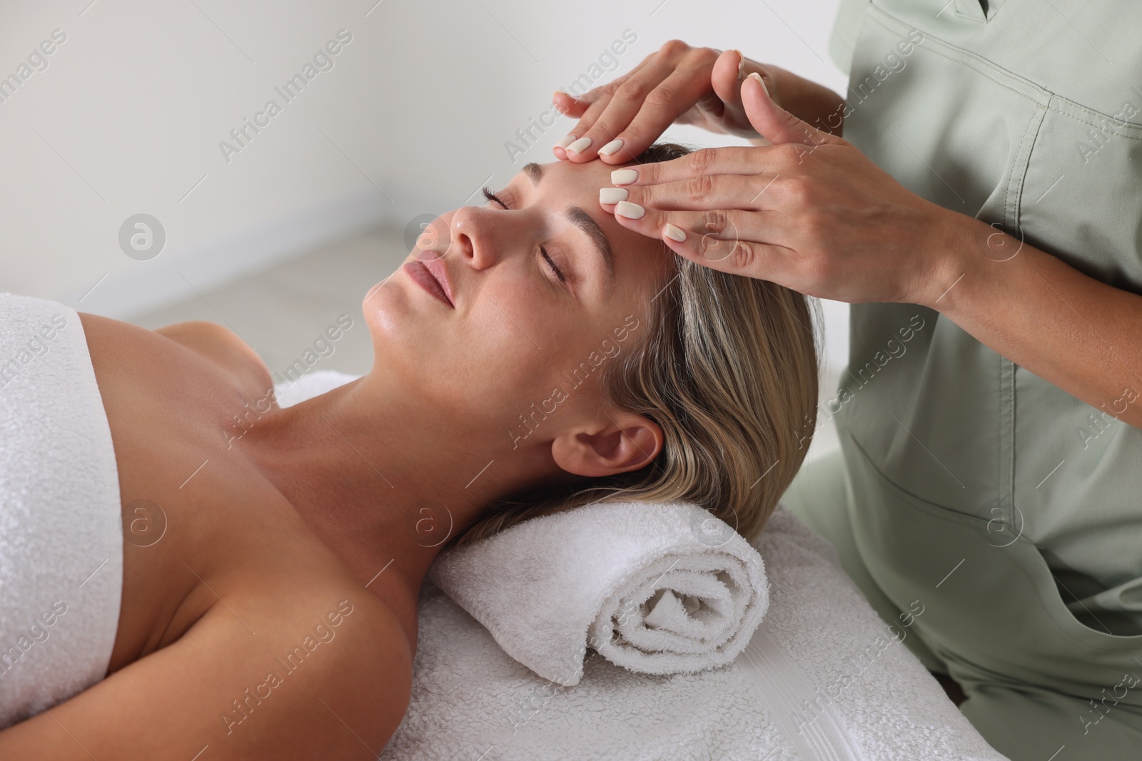 Beautiful woman receiving facial massage on couch in spa salon, closeup Photo of Beautiful woman receiving facial massage on couch in spa salon, closeup