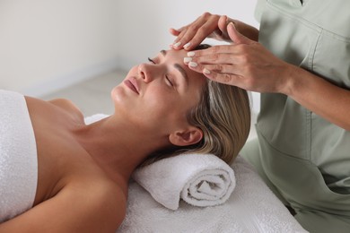 Photo of Beautiful woman receiving facial massage on couch in spa salon, closeup
