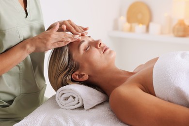 Photo of Beautiful woman receiving facial massage on couch in spa salon, closeup
