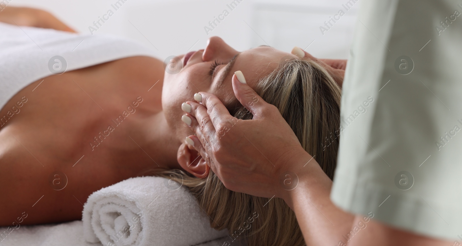 Beautiful woman receiving facial massage on couch in spa salon, closeup Photo of Beautiful woman receiving facial massage on couch in spa salon, closeup